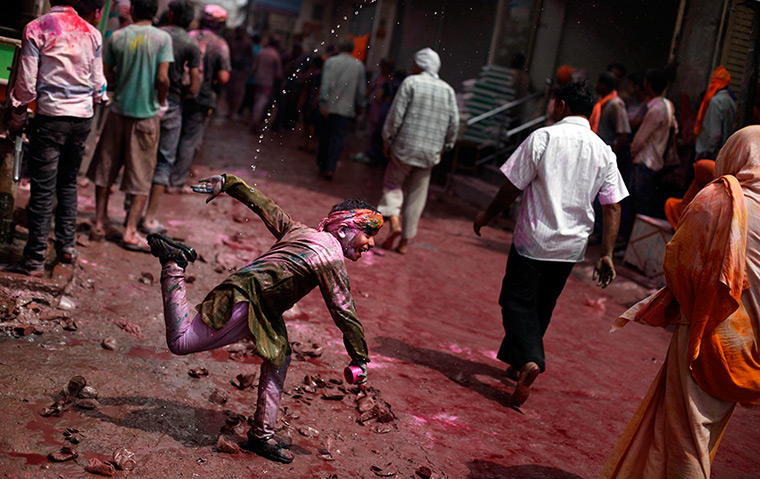 Holi festival: An Indian boy throws colored water on passers-by in Vrindavan