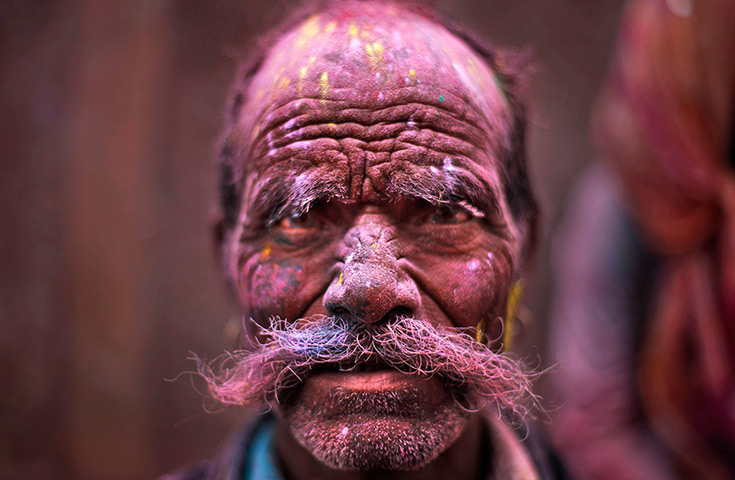 Holi festival: A Hindu devotee, face smeared with coloured powder,  Banke Bihari temple