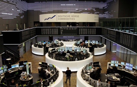 Traders are pictured at their desks in front of the DAX board at the Frankfurt stock exchange March 28, 2013.