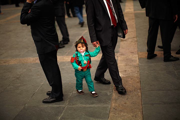 24 hours in pictures: Malaga, Spain: Child dressed up as a Spanish legionnaire, walks with her gr