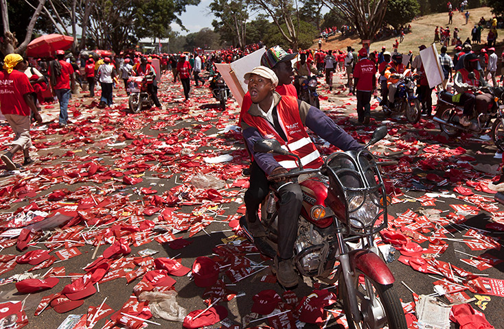 24 hours in pictures: A supporter of presidential candidate Uhuru Kenyatta's National Alliance party rides a motorbike across a sea of hats and flags at Uhuru park