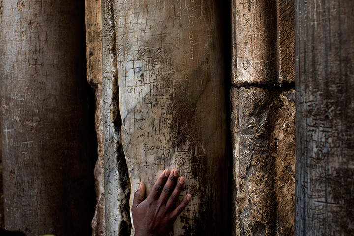 24 hours: Jeruslaem: A Christian pilgrim touches a pillar in the Church 