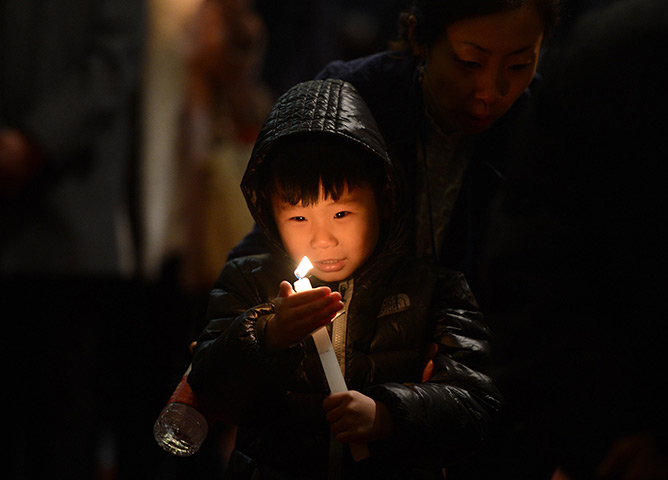 24 hours: Beijing, China: A young Catholic boy holds a candle 