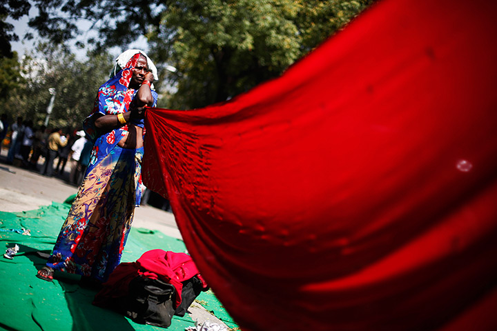 24 hours in pictures:  An Indian village woman holds her wet sari to dry 