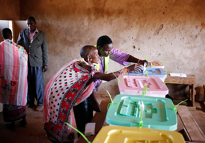 24 hours in pictures: An electoral worker helps a Masai woman to casts her ballot papers 