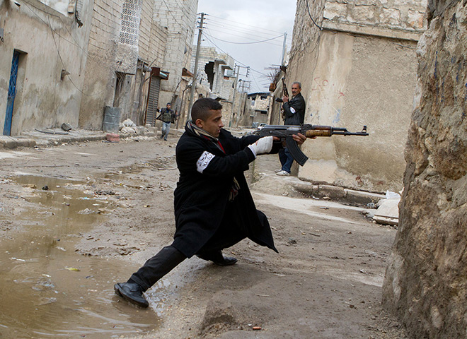 24 hours in pictures: A Syrian rebel aims his weapon during clashes