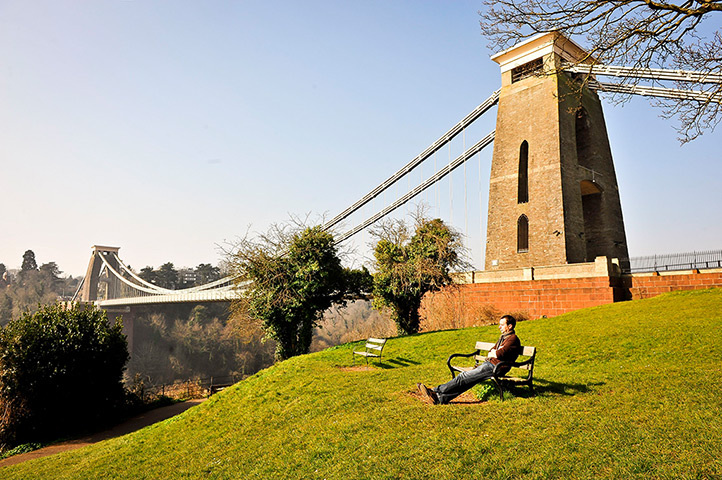 Spring weather UK: A man relaxes on a bench in sun by Clifton Suspension Bridge, Bristol