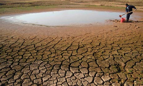 A local resident takes water from a partial dried-up pond on the outskirts of Yingtan