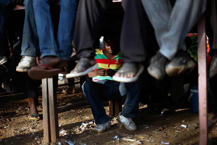 24 hours in pictures: Young men listen to others debating elections in  the Kibera slum