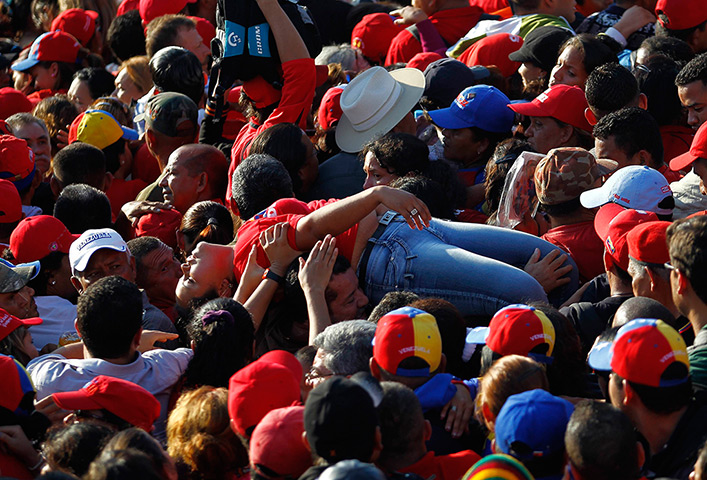 Hugo Chavez funeral: A supporter of Hugo Chavez is lifted out of the crowd after fainting