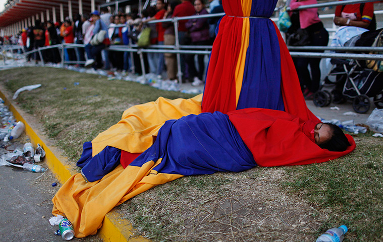 Hugo Chavez funeral: A woman wrapped in national flag colours of Venezuela's flag sleeps