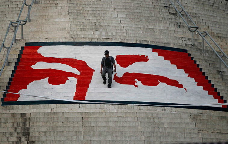 Hugo Chavez funeral: A man walks a mural of the eyes of the late Hugo Chávez on the stairs