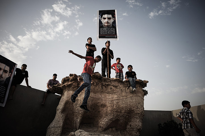 20 Photos: Bahraini youths hold a placard during the funeral of Mahmud al-Jaziri