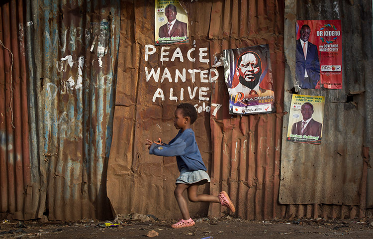 20 Photos: A girl runs past pro-peace graffiti in the Kibera slum in Nairobi, Kenya