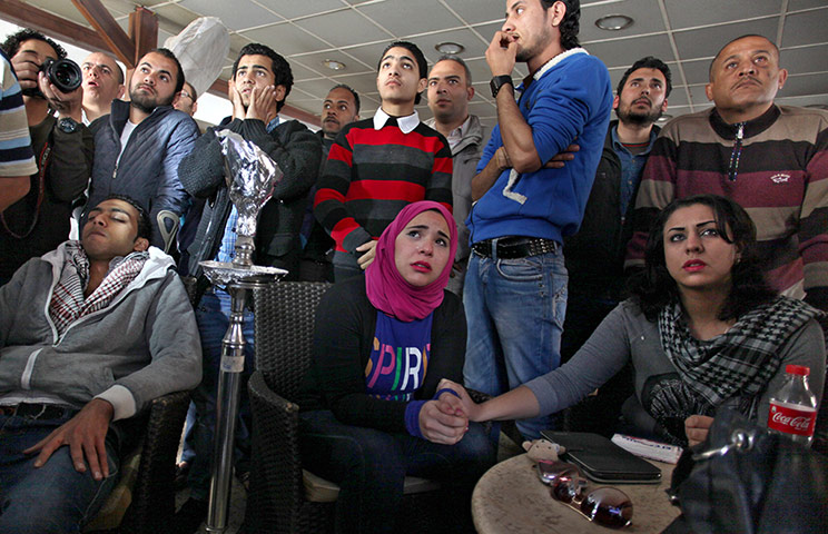 Egyptians in a coffee shop in Port Said watch the court verdict on television