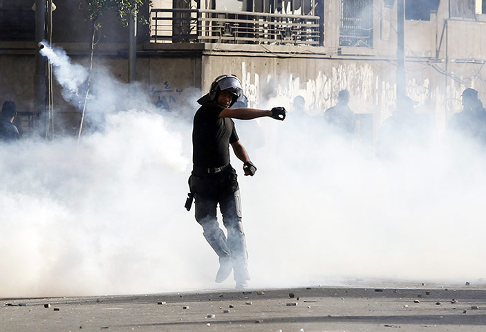 Port Said: A riot policeman throws a tear gas canister 