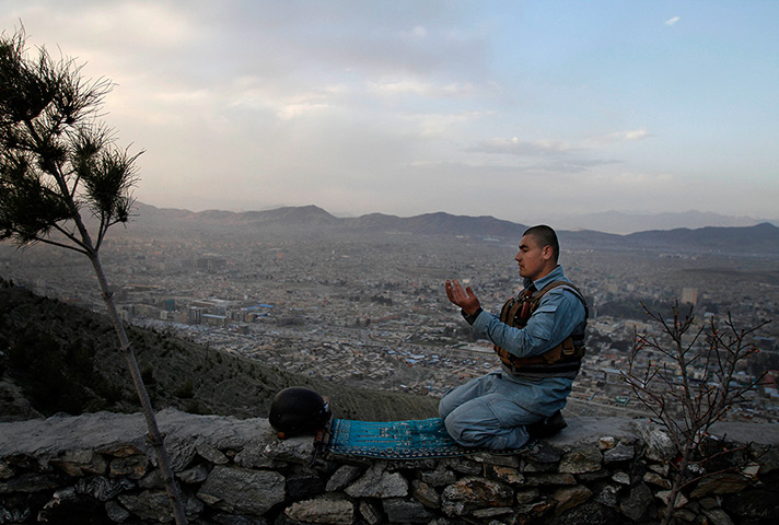 24 hours: Kabul, Afghanistan: A police man offers evening prayers on a hill