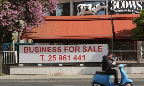 A man rides his scooter past a closed ice cream chain in the Cypriot capital Nicosia on April 9, 2013.