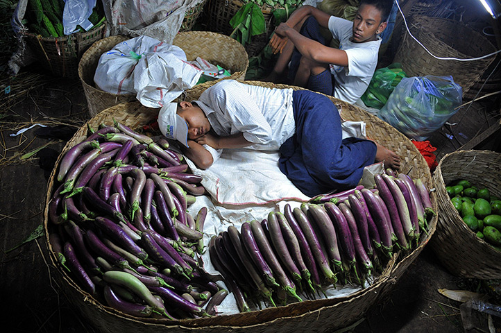 24 hours in pictures: Rangoon, Burma: A man rests in a basket at a night market 