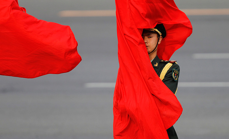 24 hours in pictures: A Chinese honor guard is wrapped by a flag