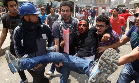 Egyptian anti-military protesters evacuate a demonstrator