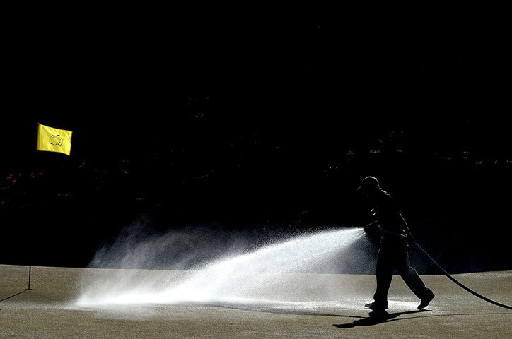 augusta day 1: A groundskeeper waters the ninth green 