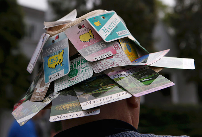 augusta day 1: A patron wearing a hat with previous years Masters spectator badges 