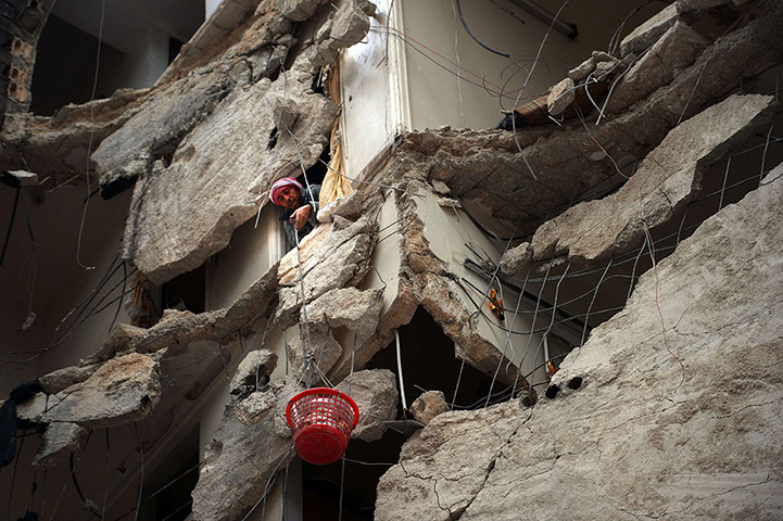 20 Photos: A Syrian man lowers a basket filled with belongings, in Aleppo