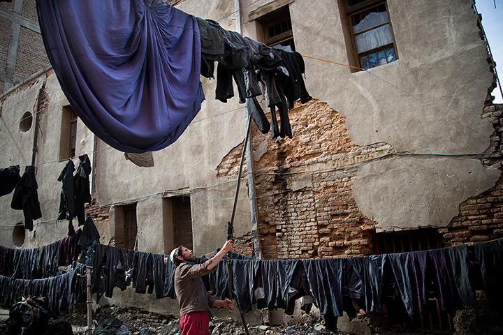 24 hours: Kabul, Afghanistan: A man hangs a freshly coloured burqas