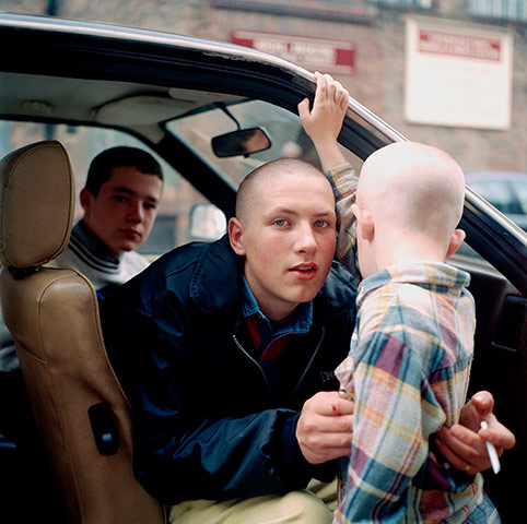 Big Picture - Rob Bremner: skinhead boy sitting in car with another boy holding young child