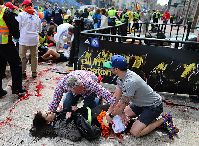 Boston explosions update: An injured woman is tended to at the finish line of the Boston Marathon