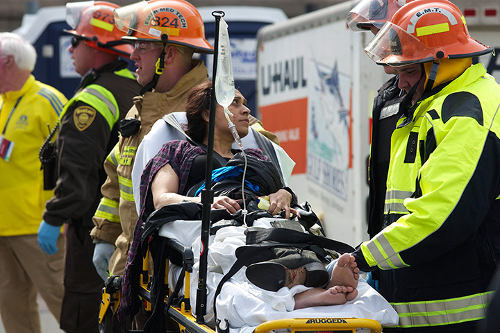 Boston explosions update: Emergency responders help an injured woman on a stretcher