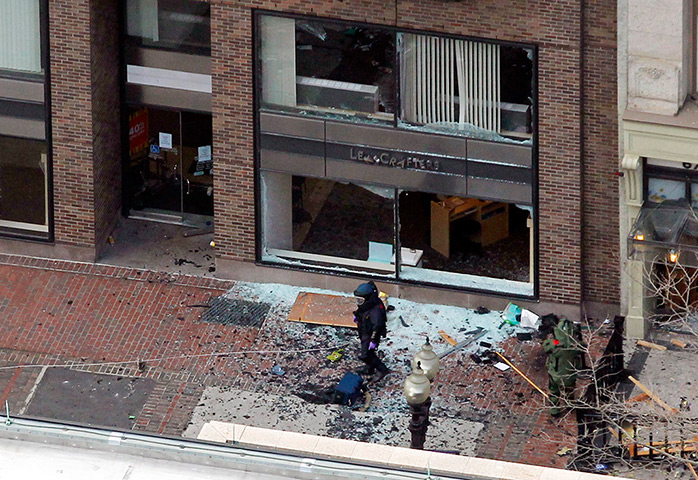 Boston explosions update: A man in a bomb-disposal suit investigates the site of an explosion on Boyl