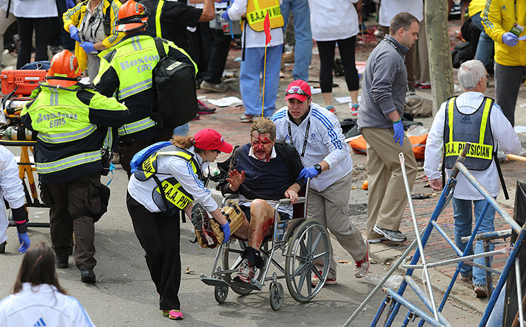 Boston explosions update: A person who was injured is taken away from the scene in a wheelchair