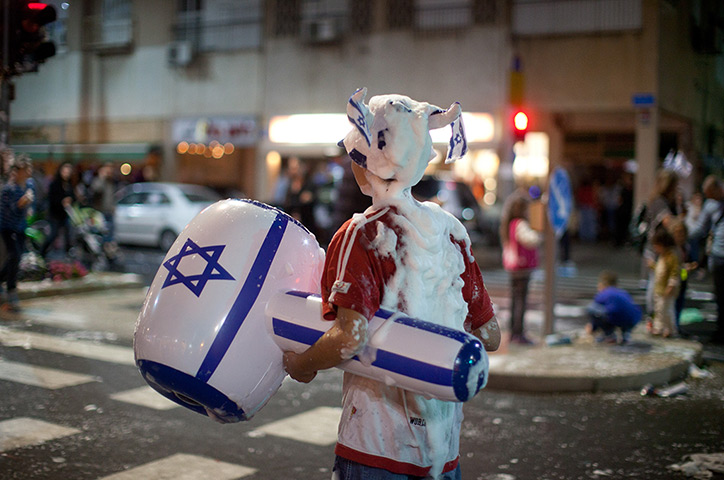 24 hours in pictures: Tel Aviv, Israel: An Israeli boy is covered with foam as Israelis celebrate