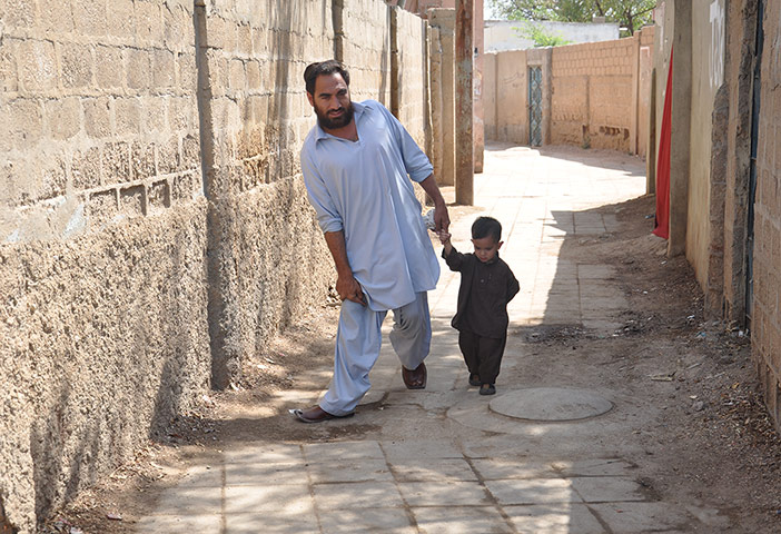 Polio victim Usman Shangla, aged 32, and his son in Pakistan