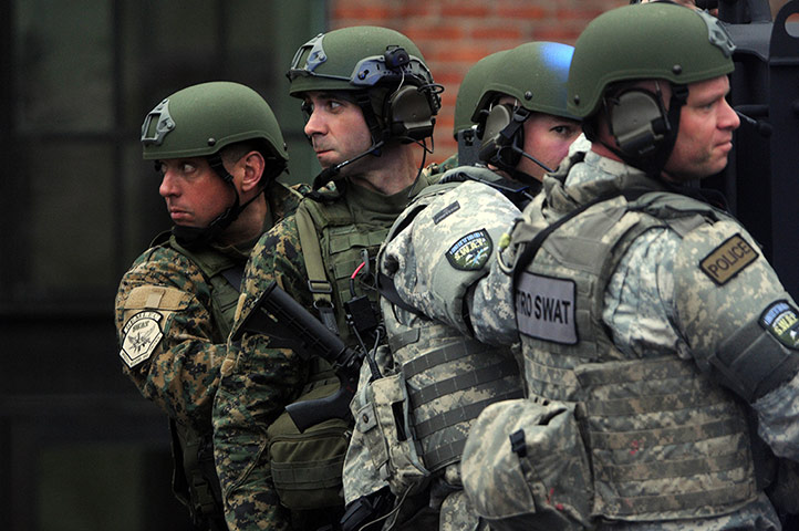 Watertown crime scene: Metro SWAT members hang off the back of a truck
