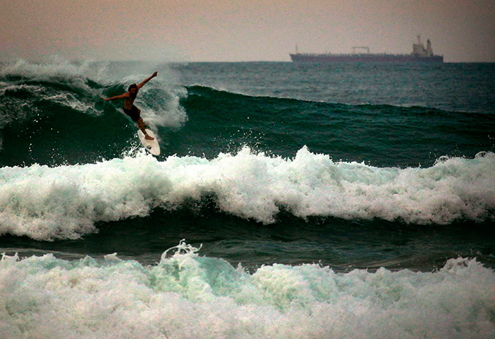 Best of sport 19/04/2013: A container ship can be seen behind a surfer