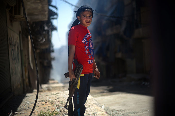 20 Photos: A Syrian boy holds an AK-47 assault rifle in Aleppo