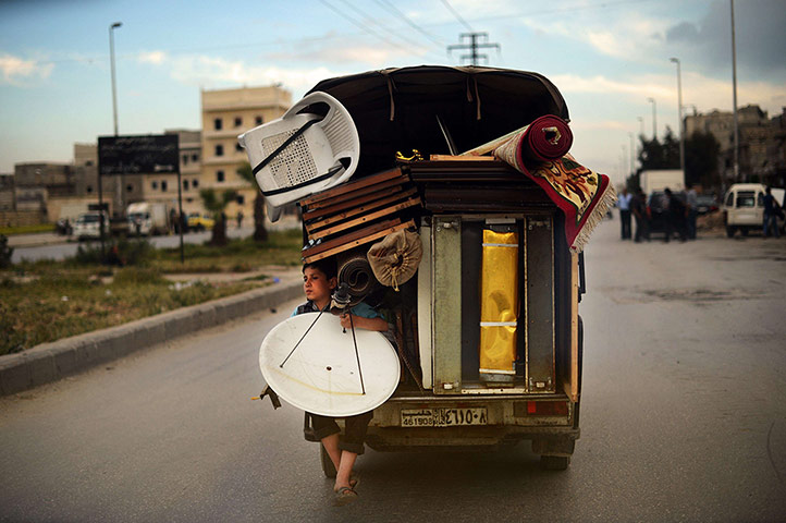 20 Photos: A boy holds a satellite antenna on the back of a truck in Aleppo