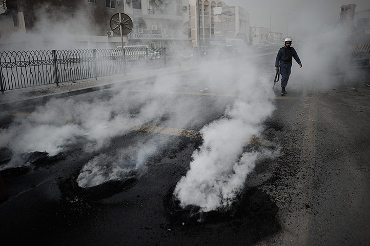 20 Photos: A Bahraini policeman walks past tyres burning during clashes