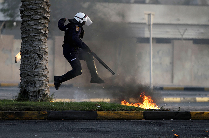 24 hours in pictures: Diraz, Bahrain: A riot policeman avoids petrol bombs thrown by Bahraini ant