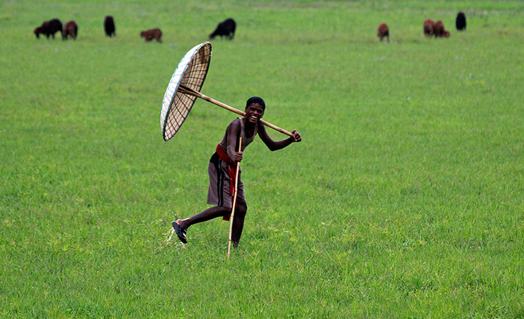 24 hours: A village boy holds a traditional handmade umbrella and reacts to the camera