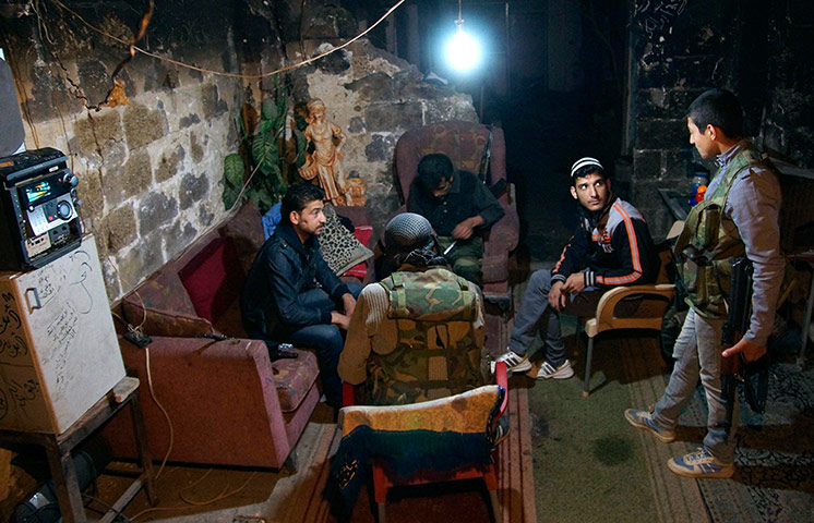 24 hours: Members of the Free Syrian army sit in a burnt house in Deir al-Zor, Syria.