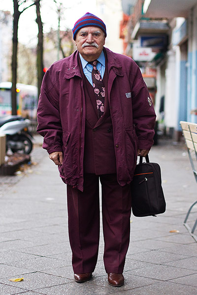 big picture - what ali : man in burgundy jacket, trousers and hat standing in street