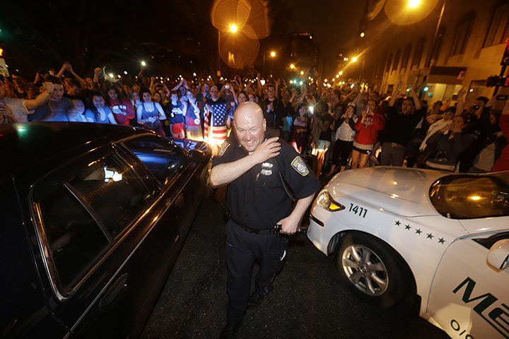 Boston bombings timeline: A police officer and crowds react to news of the capture of a suspect