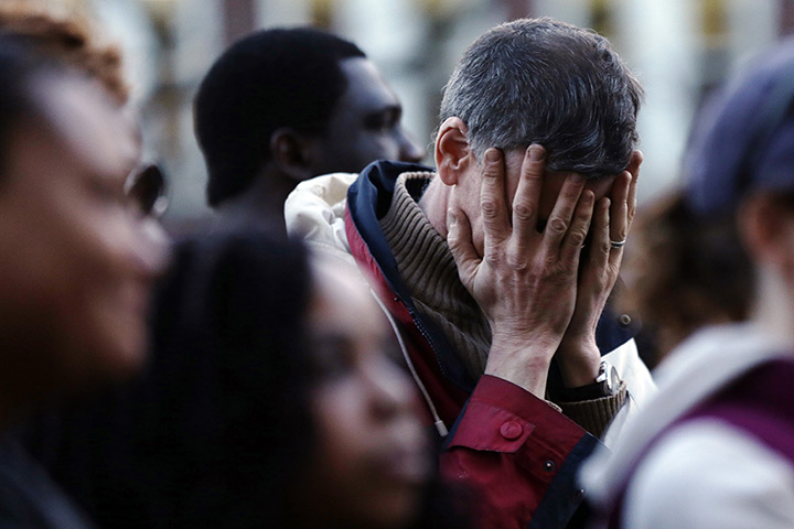 Boston bombings timeline: A mourner reacts during a candlelight vigil at City Hall 