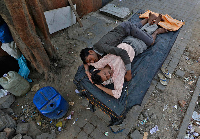 24 hours in pictures: Men sleep on a closed street vendor stall at a roadside in New Delhi