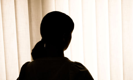A young woman, her identity hidden, in silhouette against a window