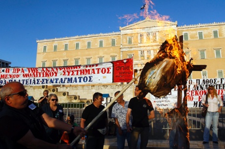 epa03680539 Protesters burn an effigy symbolizing a Greek worker during a protest rally, organized by the umbrella trade union groups General Confederation of Employees of Greece (GSEE) and the civil servants' union federation ADEDY, in front of the Greek Parliament in Athens, Greece, 28 April 2013.